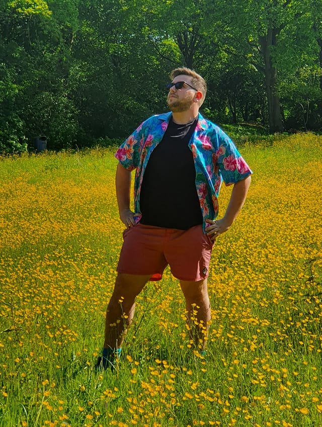 Photo of Mike standing in a green field of yellow flowers