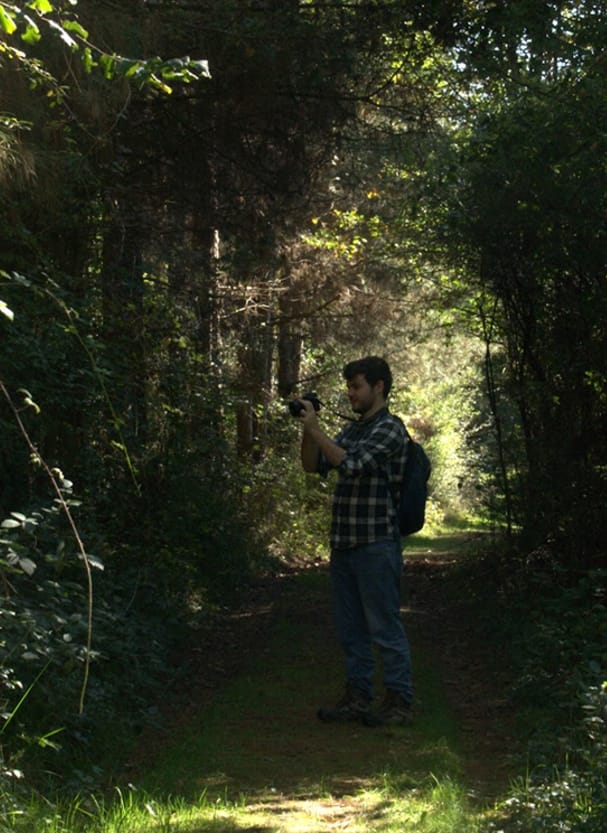 Photo of George in a forest, holding a camera